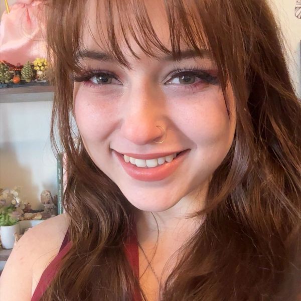 Smiling young woman with long brown hair and a nose ring.