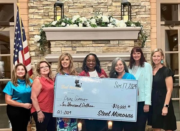 Group of women holding a large $10,000 donation check from Steel Mimosas.