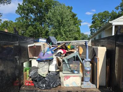 A dumpster filled with various discarded household items and trash.