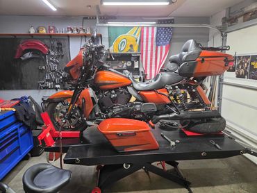 Orange Harley-Davidson motorcycle undergoing maintenance in a garage.