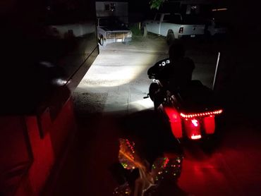 Motorcycle with bright red taillights rides at night on a dimly lit street.