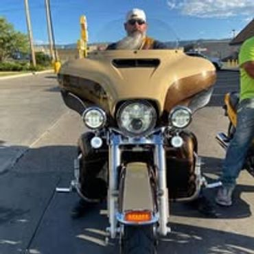 Man with a beard sitting on a brown motorcycle with a large front fairing.