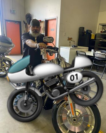 Man with a beard sitting on a motorcycle inside a garage.