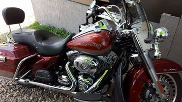A shiny red Harley-Davidson motorcycle parked on gravel.