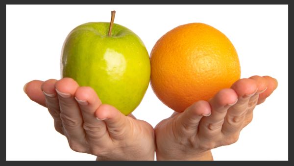 Hands holding a green apple and an orange.