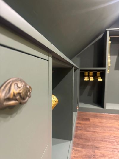 Close-up of a green cabinet with brass handles in a room with wooden flooring.