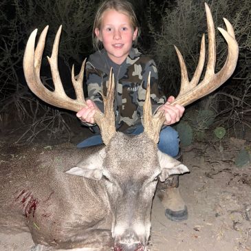 Young hunter with a large deer at night.
