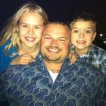 Smiling father with two children at night.