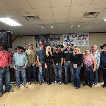 Group of people standing indoors in casual and western attire.