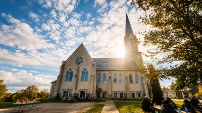 A bright sunny day at a church with people gathered outside.