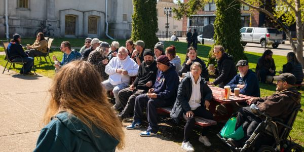 Group of people sitting and talking outdoors on a sunny day.