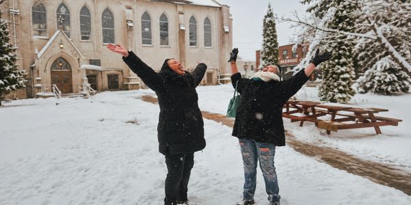 Two people enjoying the snow outside a church.