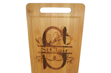 Wooden cutting board with engraved decorative letter and name.