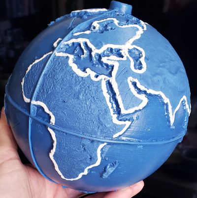 The finished blue globe being held in a hand.