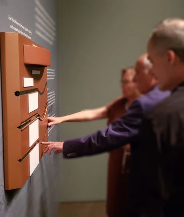 People using the board mounted at the Denver Art Museum.