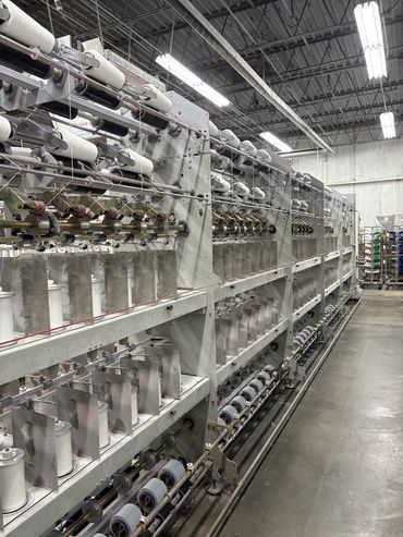 Industrial textile machine spinning white yarn in factory.