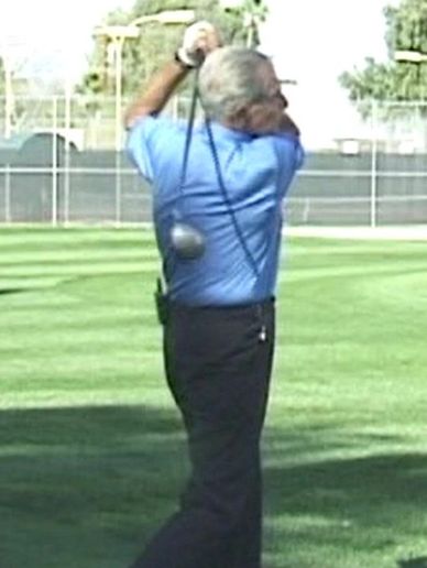 Man swinging a golf club on a golf course.
