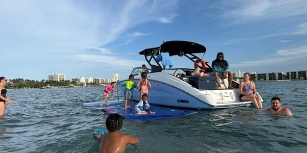 Group of people enjoying time on and around a Yamaha boat in the water.