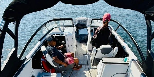 Two people enjoying a boat ride on calm waters under a canopy.