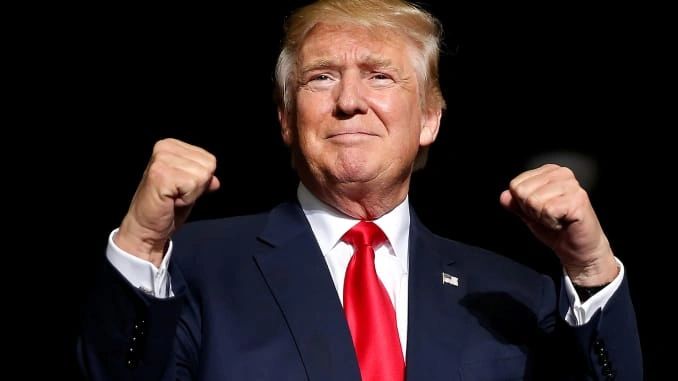 A man in a suit raising his fists confidently.