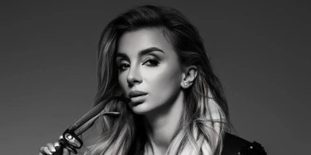 Black and white portrait of a woman holding sunglasses near her lips, exuding confidence.