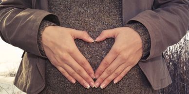 Heart-shaped-hand-over-pregnancy -bump-in-winter-clothes