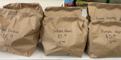 Brown paper bags labeled with bean varieties and prices on a table.