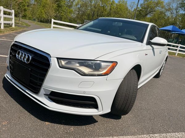 White Audi sedan parked outdoors on a sunny day.