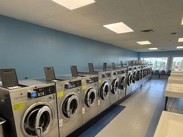A row of industrial washing machines in a clean laundry room.