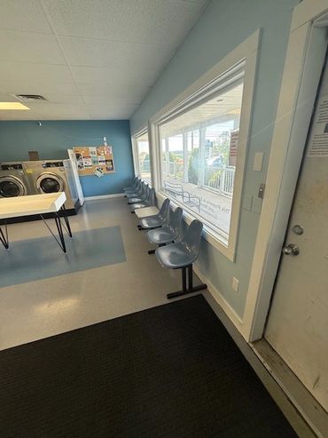 Empty laundromat waiting area with chairs and washing machines.