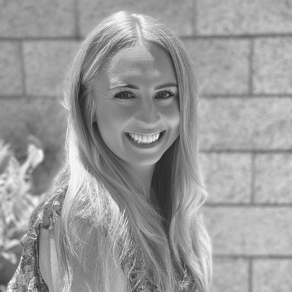 Smiling woman with long hair against a brick wall.