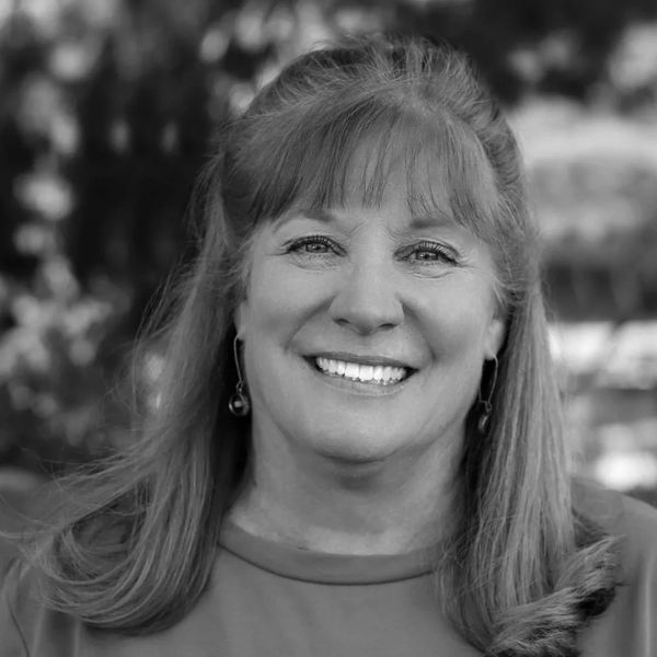 Smiling woman with earrings and long hair in black and white.