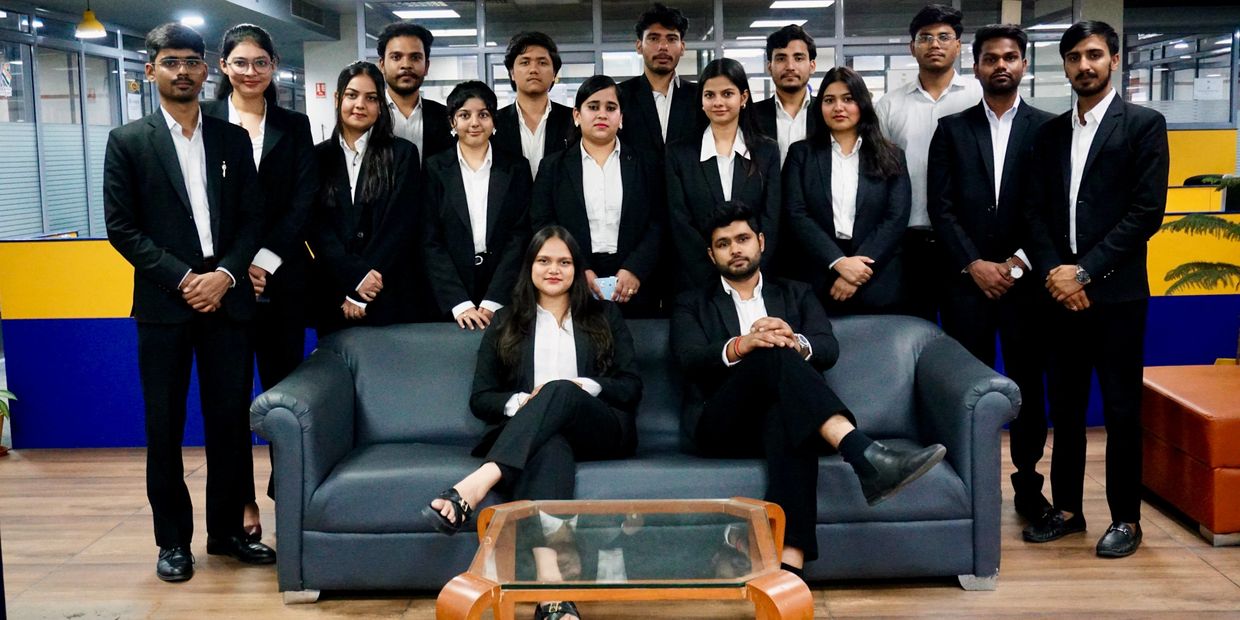 Group of young professionals in black suits posing in office.