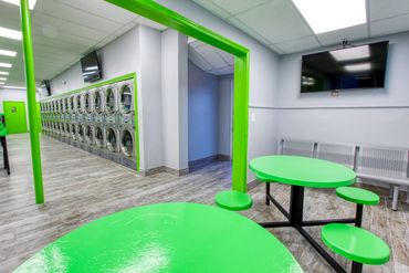 Room with tables to lounge, have a snack and watch tv at Mary’s Laundromart.