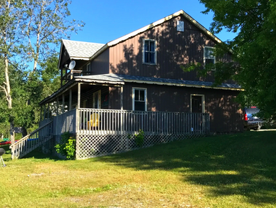 Brown cabin with blue sky and green grass.