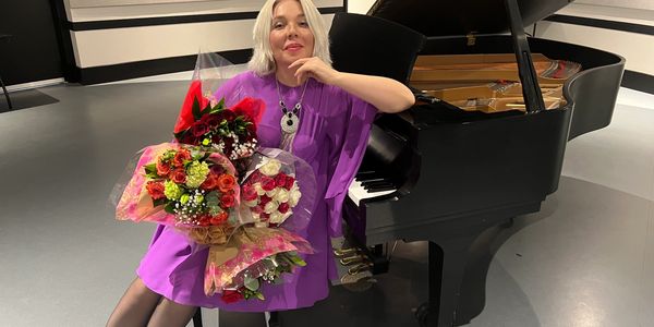 Dr. Maria Pisarenko with flowers at a grand piano after a concert, Las Vegas