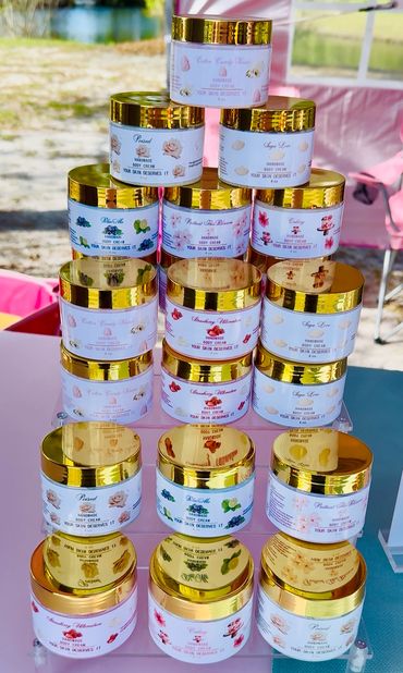 Stacked jars of handmade body cream with gold lids on display.