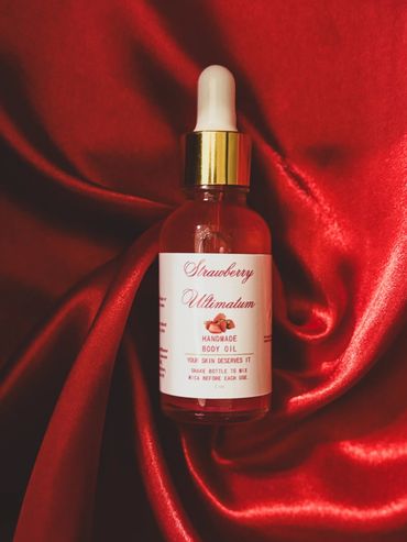 A bottle of strawberry-scented handmade body oil on red satin fabric.
