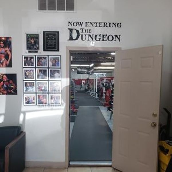 Entrance to a gym area labeled 'The Dungeon' with motivational photos on the wall.