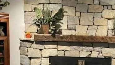 Stone fireplace with wooden mantel and decorative plants. Poconos