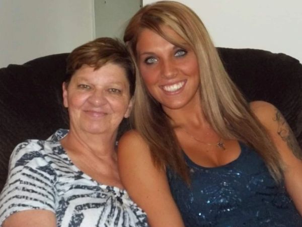 Two women sitting closely, smiling at the camera.