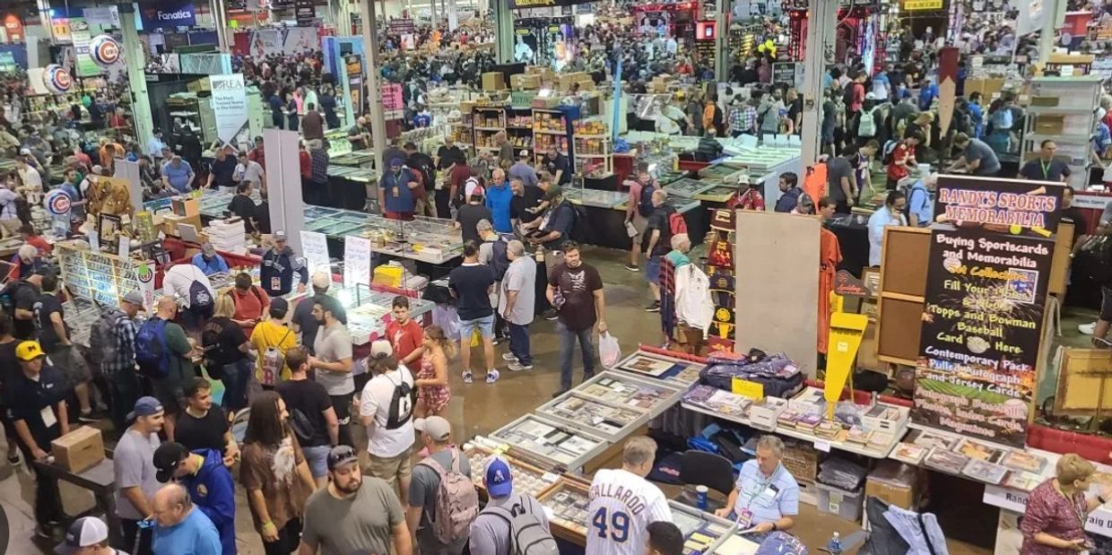 Crowded sports memorabilia convention with many attendees browsing booths.