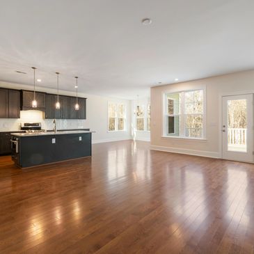 Spacious open kitchen and living area with dark cabinets and hardwood floors.