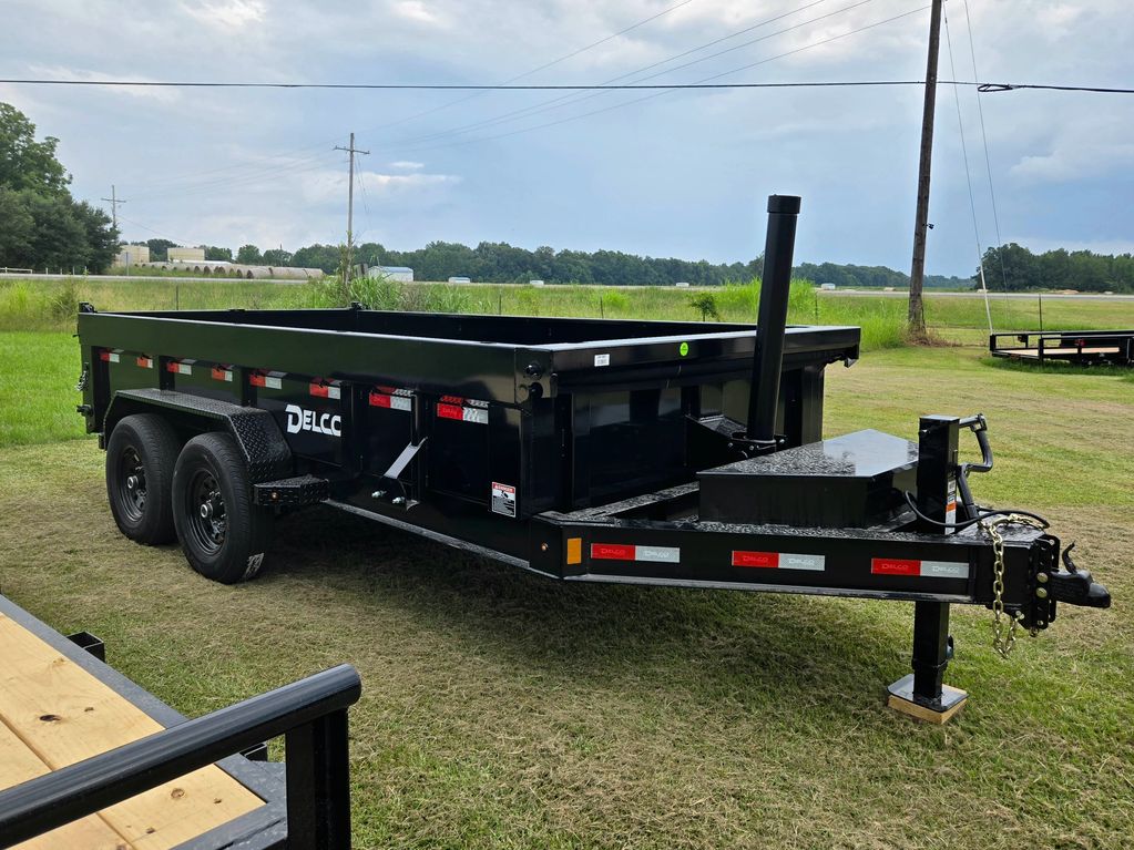 Black Delco dump trailer parked on grass under cloudy sky.