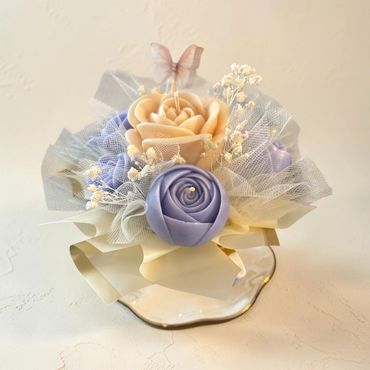 Lilac and ivory candle roses inside an ivory teacup with gold trim, tulle and baby’s breath
