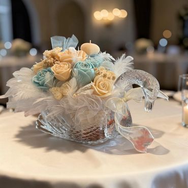 Centerpiece of Soft blue/ivory candles roses in a crystal swan vase with feathers & baby’s breath.
