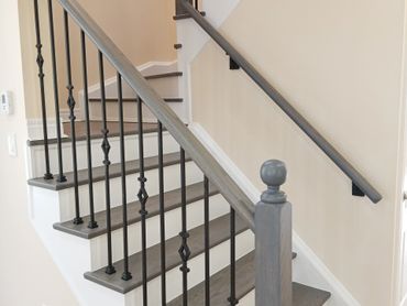 Modern indoor staircase with wooden steps and black metal railings.