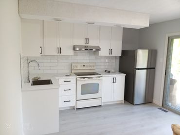 Modern kitchen with white cabinets, stainless steel fridge, and light gray flooring.