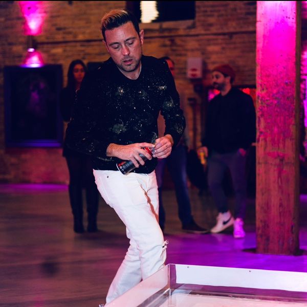 Man playing a game indoors under purple lighting, holding a can.