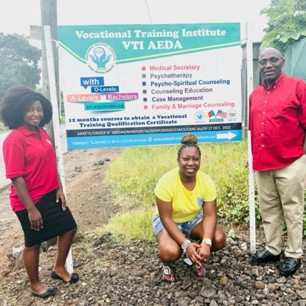 Three people posing near a Vocational Training Institute signboard outdoors.